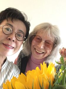 Sakiko Yamaoka with Susann Johnson in front of a bouquet of yellow tulips