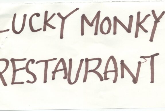 Notebook page from Step 2 with the words 'Lucky Monky Restaurant' in thick black marker