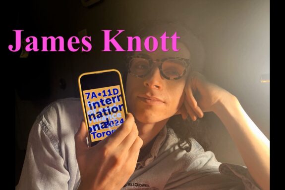 In this screen shot from Margaret Dragu's Typical Day: James Knott illustrated audio podcast, a person wearing tortoise shell glasses faces the camera. The name James Knott appears in pink letters across the upper part of the screen. James's head is propped against one arm. In their other hand, they hold a cellphone, face turned toward the camera, with the 2024 7a*11d International Festival of Performance Art logo displayed.