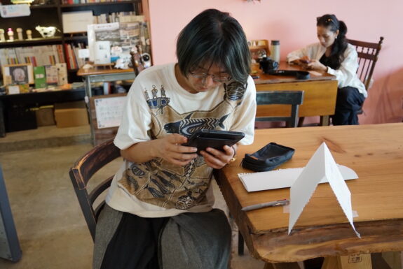 A man with glasses sits at a table, looking at an iPad.