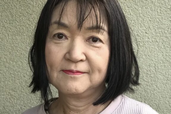 Head shot of a woman with dark, shoulder-length hair, wearing a pink sweater.